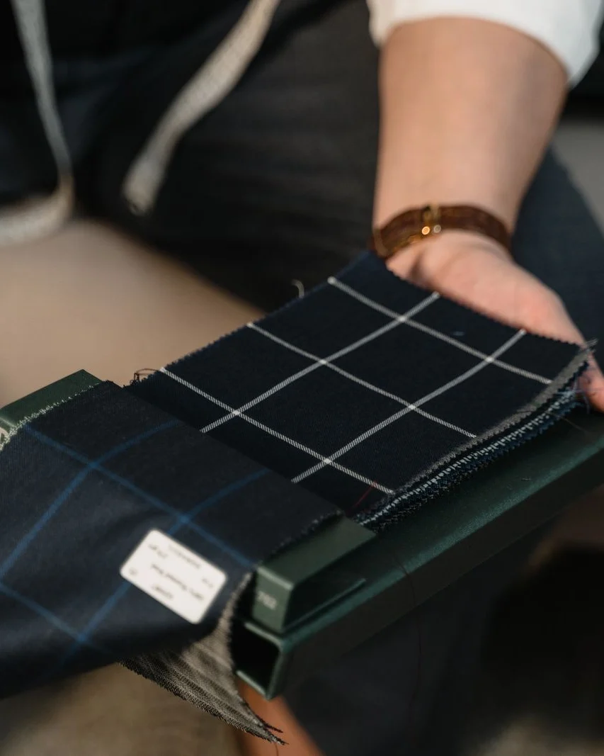 Échantillons de lainage à carreaux et leur étiquette, tenus en main